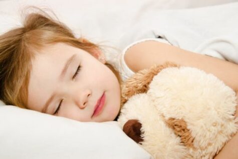 Adorable little girl sleeping in the bed with her toy